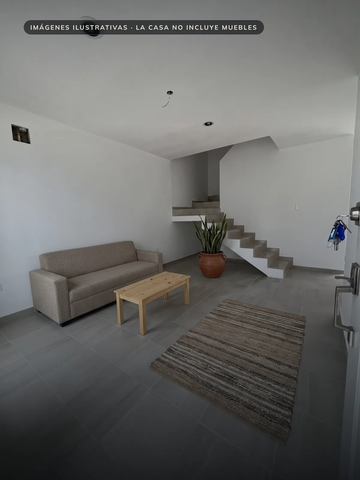 Sala en planta baja con la escalera al fondo, mostrada con muebles ilustrativos