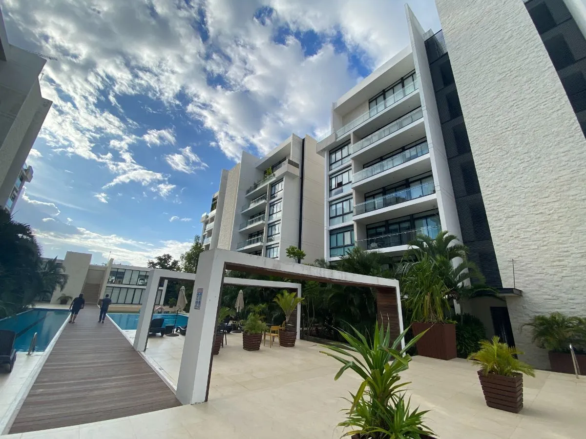Alberca, andador de madera y arquitectura blanca de La Vista Luxury Towers bajo cielo despejado