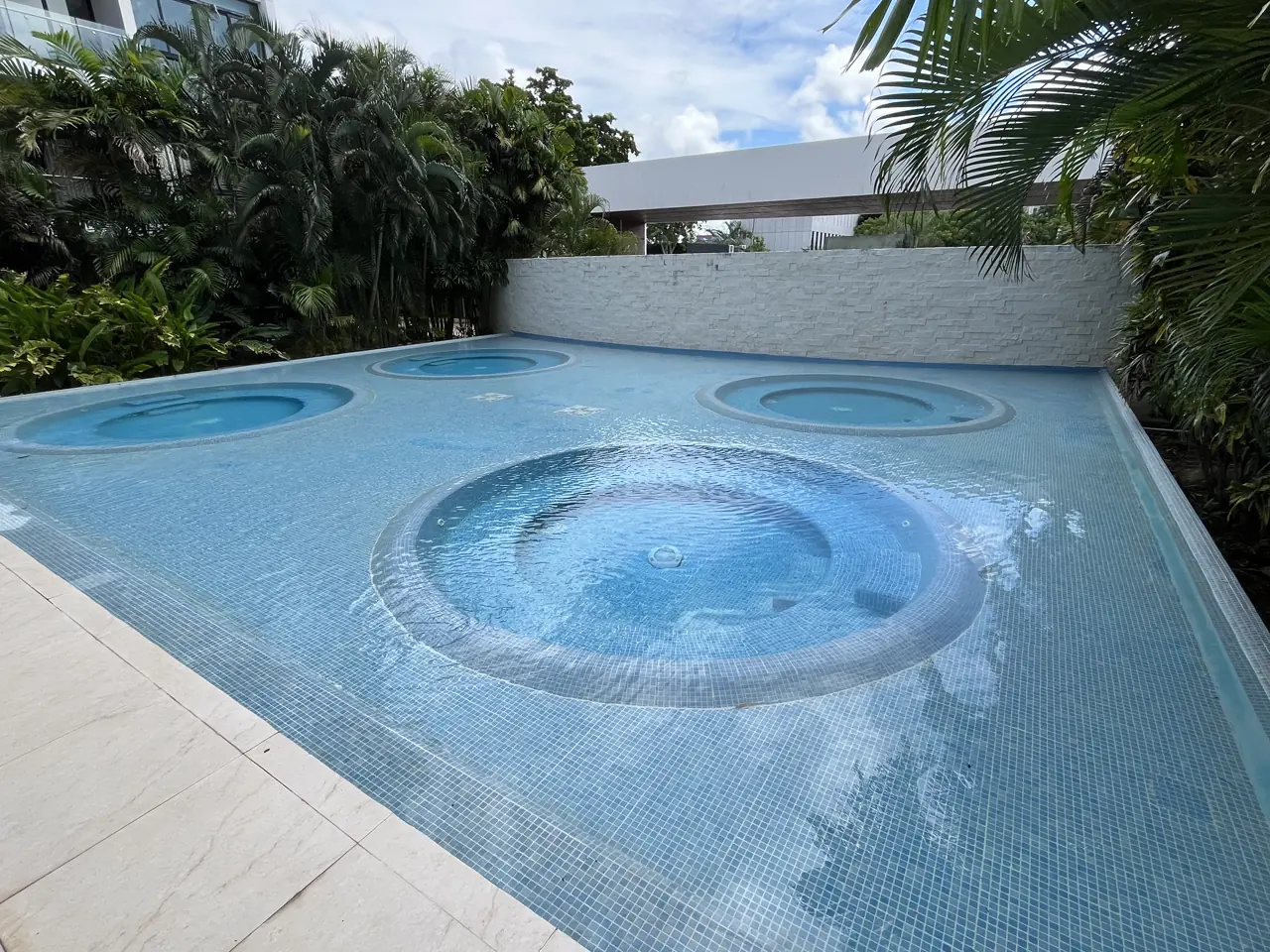 Cuatro jacuzzis circulares embebidos en una alberca de mosaico azul