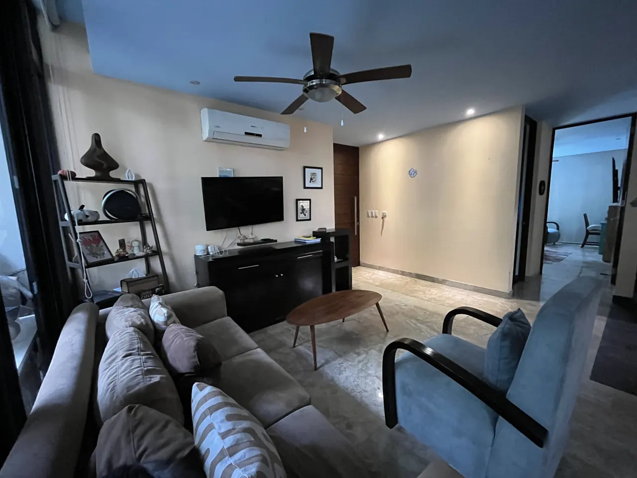 Sala amueblada con sofá de tres plazas, sillones y pantalla frente al ventanal