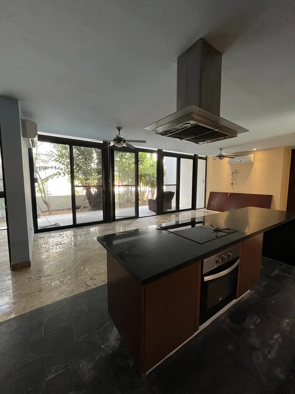 Isla de cocina con parrilla, horno y campana central frente a la terraza