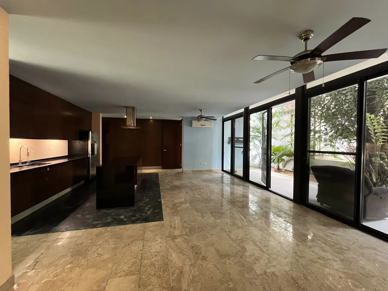 Cocina, comedor y sala en planta abierta con piso de mármol travertino